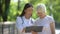 Smiling nurse showing elderly woman examination results in hospital park