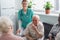 Smiling nurse sitting near senior interracial