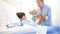 Smiling nurse takes care of a child lying in hospital bed making him a surprise by giving him a teddy bear