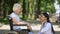 Smiling nurse talking with disabled elderly woman in park, rehabilitation center