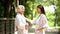 Smiling nurse talking with elderly woman in bathrobe at sanatoria park, relax