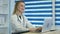 Smiling nurse typing on laptop and making notes at reception desk