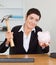 Smiling office worker breaking a piggy bank