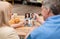 Smiling old caucasian husband and wife communicate with different people on tablet screen