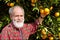 Smiling old farmer shows orange fruit