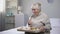 Smiling old woman eating dinner in nursing home, social security for aged people