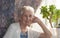 Smiling old woman near the window. Happy senior woman sitting near window with flowers.