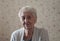 Smiling old woman near the window. Happy senior woman sitting near window at home