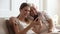 Smiling older father with adult daughter using phone together