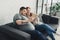 Smiling overweight boyfriend and girlfriend reading book on sofa