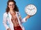 Smiling paediatrician doctor showing clock on blue