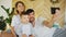 Smiling parents with baby taking selfie family photo on bed at home