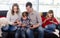 Smiling parents with children spending time playing with smartphones