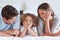 Smiling parents lying on a bed with their son