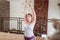 Smiling peaceful lady in light sleeveless t-shirt raising connected hands