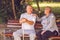 Smiling pensioner couple sitting on a park bench