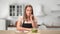Smiling pensive housewife in apron on diet choosing between sweet doughnut and fresh vegetable salad