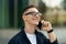 Smiling pensive millennial caucasian man in glasses enjoy communication, calling by phone