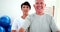 Smiling physiotherapist helping elderly patient lift hand weights