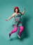 Smiling plus-size fat chubby woman in funny hat and colorful clothes jumps high or walk skipping on popular mint
