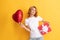 smiling pondering redhead woman with red heart balloon and gift box. be my valentine