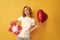 smiling pondering redhead woman with red heart balloon and gift box. be my valentine
