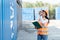 Smiling portrait of beautiful asian female industrial engineer wearing white helmet, vest holding walkie talkie. Safety Supervisor