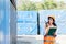 Smiling portrait of beautiful asian female industrial engineer wearing white helmet, vest holding walkie talkie. Safety Supervisor