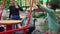 Smiling positive children pushing wheelchair with disabled friend on merry go round outdoors. Happy Caucasian boy and