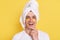 Smiling positive man wrapped towel on head doing morning cosmetology procedures, posing with patches under eyes isolated over