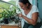 A smiling and positive mature woman fertilizing plants on the balcony