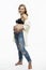 Smiling pregnant blonde woman in jeans. Tenderness in anticipation of the baby. Full height. White background. Vertical