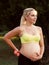 Smiling pregnant woman caress her belly at nature