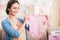 Smiling Pregnant Woman with Pink Baby Romper.