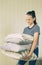 Smiling preteen girl holding stack of pillows and blankets. Homework, home textile