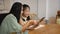 Smiling preteen girl sitting with mother in kitchen and having learning online at virtual class. Concept of Virtual