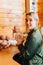 Smiling pretty caucasian young woman holding newborn baby doll in arms while sitting near collection of handmade children toys