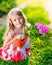 Smiling pretty little girl squatting and holding purple flower