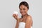 Smiling pretty millennial african american woman with perfect skin in towel with cream on shoulder showing jar