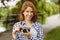 Smiling pretty redhead holding her camera