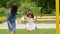 Smiling Pretty Woman Rides Her Daughter on the Swing on the Playground During Summer Warm Day.