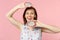 Smiling pretty young girl in summer clothes holding half of fresh ripe pitahaya dragon fruit isolated on pink pastel