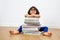 Smiling primary child with eyeglasses leaning on pile of books