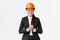 Smiling professional asian businesswoman in safety helmet and business suit introducing enterprise to clients or