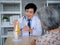 Smiling professional Asian man orthopedic doctor in white suit pointing to knee joint anatomy model.