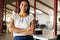 Smiling professional businesswoman in casual, with arms crossed standing in office.