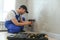 Smiling professional electrician in uniform replacing a socket in apartment after renovation work