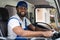 Smiling professional man mover worker in blue uniform driving truck to delivery and moving house service