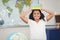 Smiling pupil balancing books on head in a classroom