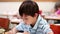 Smiling pupil writing on his notebook